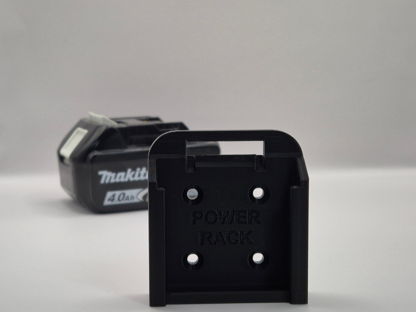 Black power rack with Makita battery on a gray background